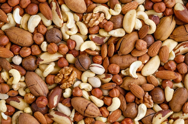 Photo almonds, hazelnuts, cashews, brazilian nuts, walnut, macadamia, pecans and pistachios mixed together. natural background. healthy food. top view.