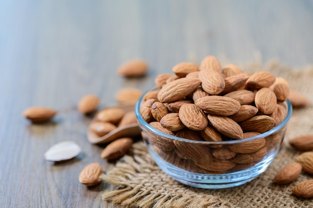 Almonds nut with leaves in glass cup on wood background They are highly nutritious and rich in healthy fats or Highdensity lipoprotein HDL cholesterol antioxidants