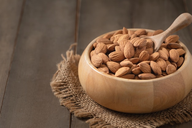 Almonds nut and wood spoon in wood cup on wood background They are highly nutritious and rich in healthy fats or Highdensity lipoprotein HDL cholesterol antioxidants vitamins and minerals