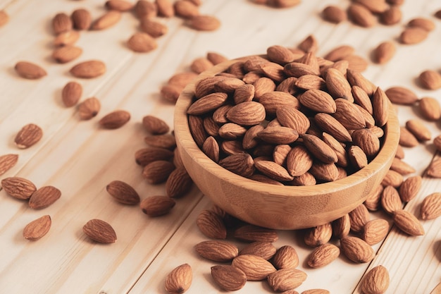 Almonds nut in wooden bowl and pour on table with copy space. Almonds nut is healthy diet food which high protein low fat and essential amino acid.