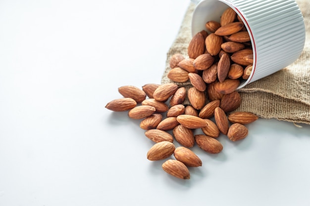 Almonds pouring from cup with sack