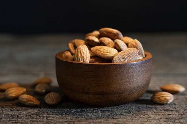 Almonds seed in wooden bowl on wooden table background.