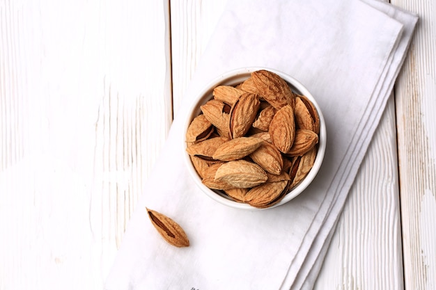 Almonds in shell on a white wooden background