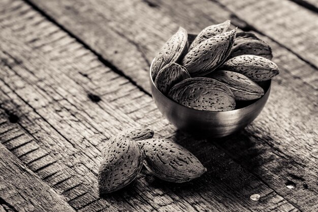 Almonds in shell on wooden background monochrome