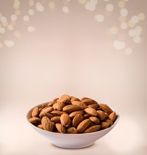 Almonds in white bowl on beige background.