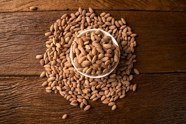 Almonds in white bowl on wooden background