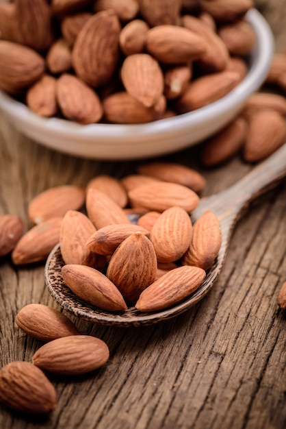 almonds in a white ceramic bowl on grained wood background