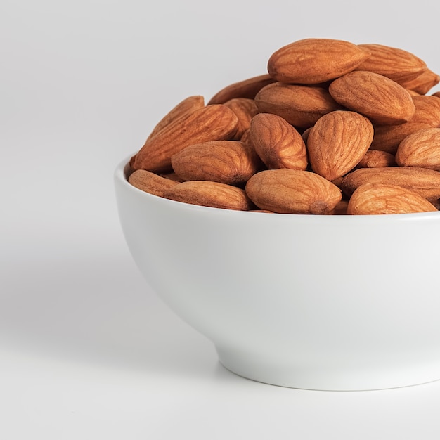 Almonds in a white Cup on a white background.