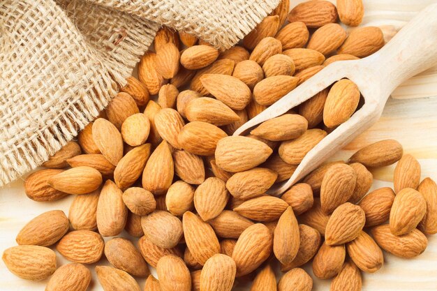 Almonds with wooden scoop on wooden table