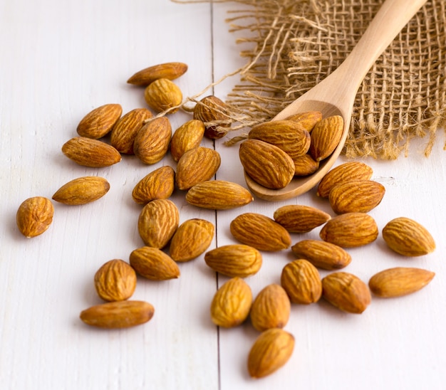 Almonds with wooden spoon on the wooden table. 