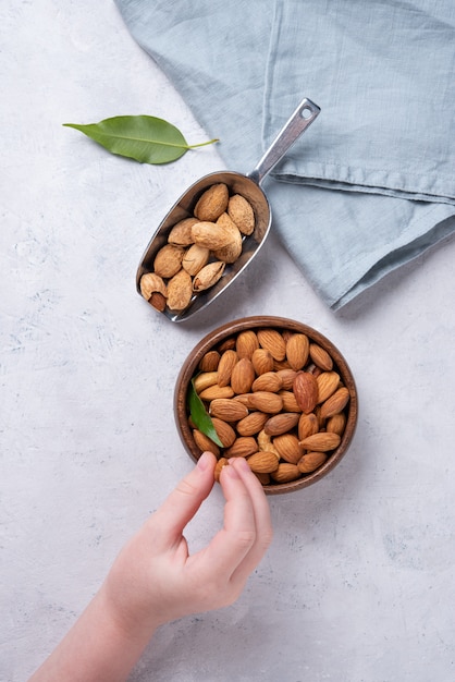 Almonds on wooden bowl on gray background