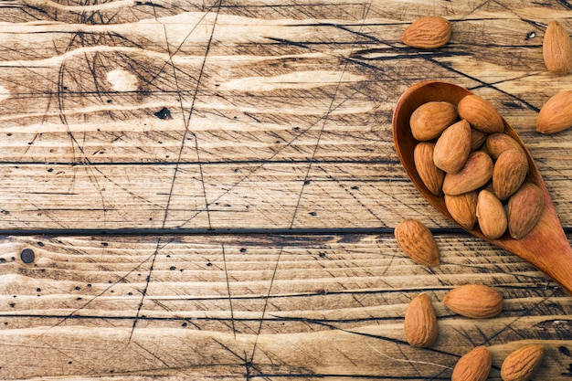 Almonds in wooden spoon on wooden background.