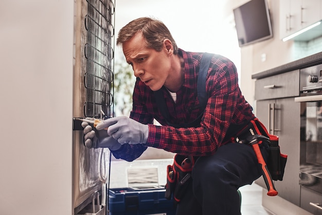 Almost done senior male technician checking refrigerator