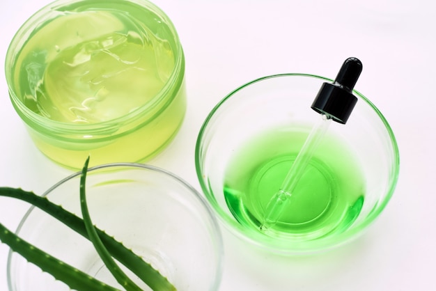 Aloe gel, aloe vera leaves and green serum from natural ingredients on a white background. Making cosmetics at home