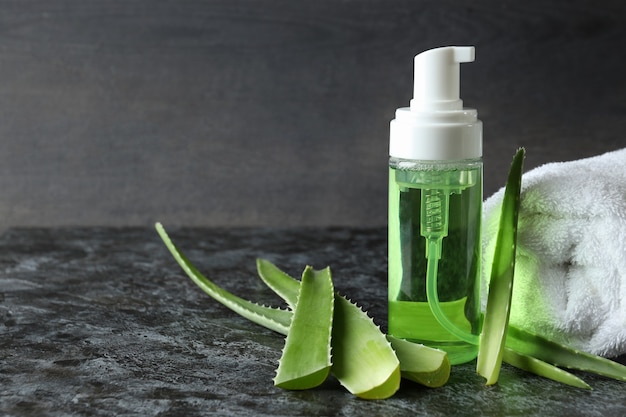 Foto foglie di aloe, cosmetici e asciugamano sul tavolo affumicato nero