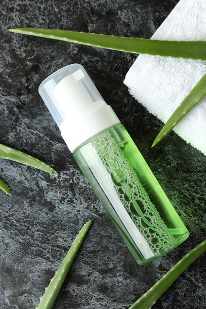 Foglie di aloe, cosmetici e asciugamano sul tavolo affumicato nero