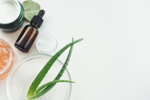 Aloe leaves moisturizing cream, mask and tonic on a white table. Creating natural makeup products at home. Mixing natural extracts to produce anti-aging serum