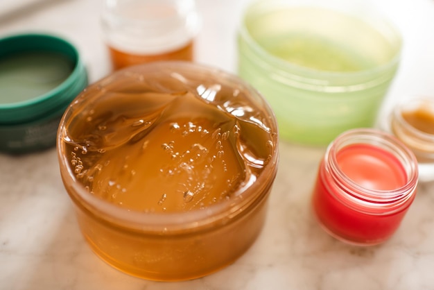 Aloe or snail mucin gel in plastic jar with skin care products on table in bathroom close up Selective focus