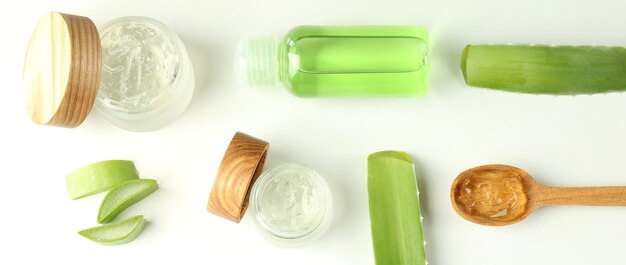 Cosmetici, foglie e fette di aloe vera su fondo bianco