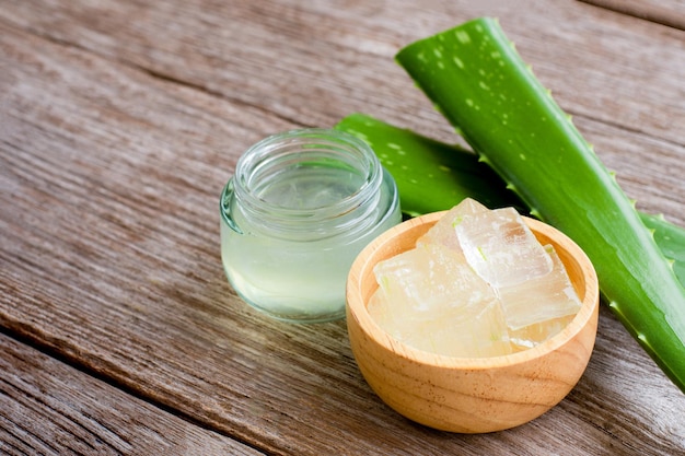 Olio essenziale di aloe vera e gel di aloevera con foglia verde di cactus su sfondo di tavolo in legno