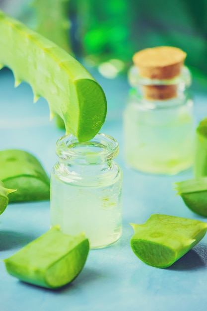 Aloe Vera extract in a small bottle and pieces on the table. Selective focus.