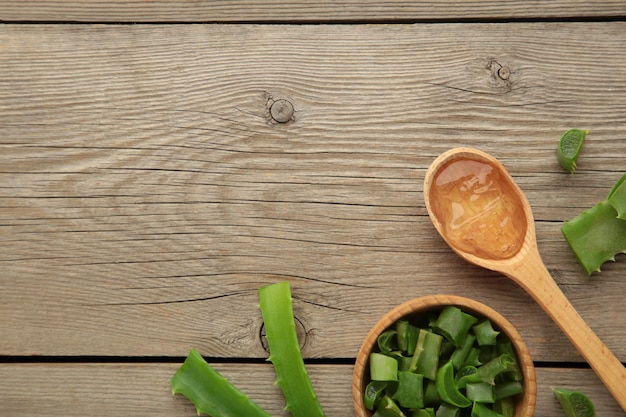 Aloe vera gel on wooden spoon with aloe vera on grey wooden background. Top view.