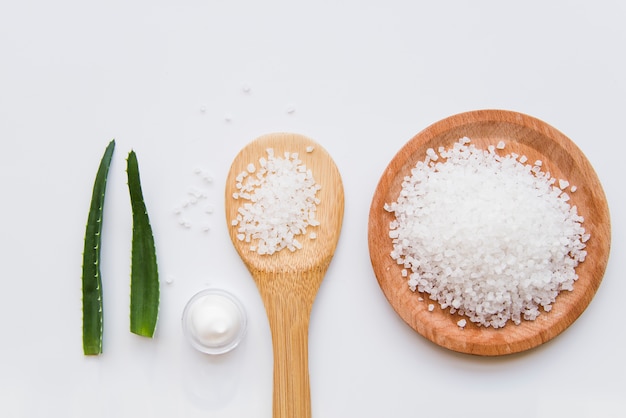 Foto foglie di aloe vera; crema idratante della pelle e del sale marino su fondo bianco