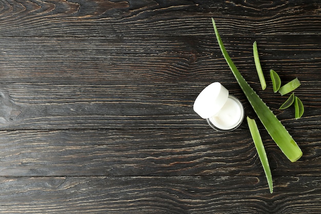 Aloe vera leaves, slices and cream on wooden background