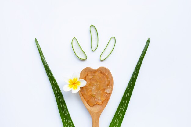 L'aloe vera lascia con le fette e gel sul cucchiaio di legno. isolato su bianco