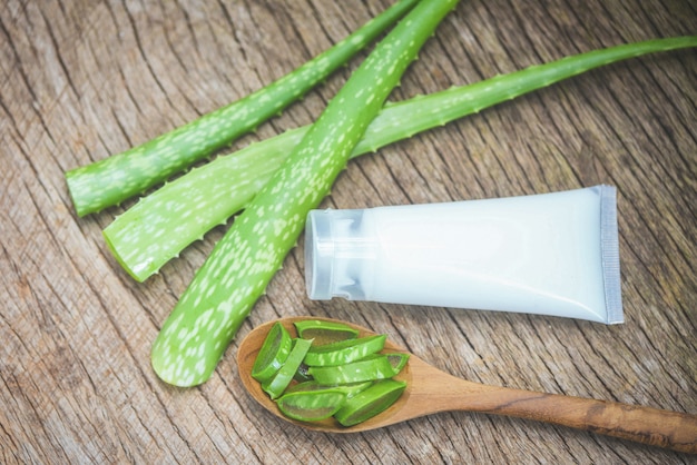 Fetta della pianta dell'aloe vera e bottiglia della lozione su fondo di legno rustico / foglia fresca dell'aloe vera con le erbe naturali del gel e le medicine di erbe