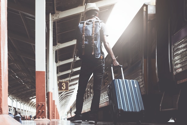 Alone asian travelling with backpacker and suitcase for travel by train in Thailand