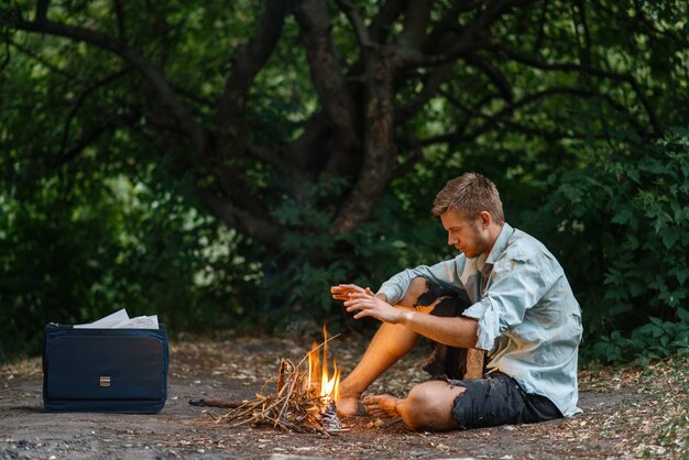 Alone businessman warms by the fire on lost island