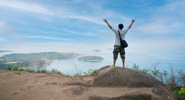 Alone happy man photographer or traveler standing and thinking\
something and see beautiful scenery landscape nature view on rock\
mountain in phuket thailand