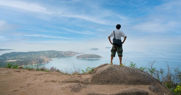 Alone happy man photographer or traveler standing and thinking\
something and see beautiful scenery landscape nature view on rock\
mountain in phuket thailand