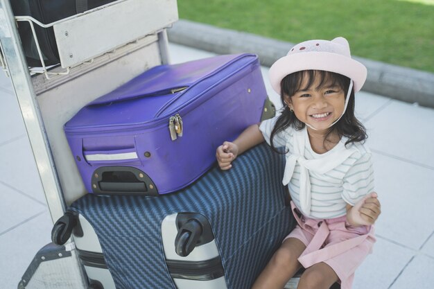 写真 空港でスーツケースの横に座っている一人の少女