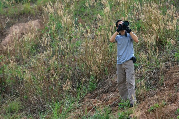 Alone man taking photos with hills and grassy fields as the backdrop