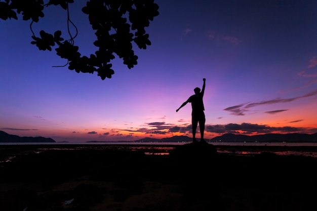 Turista da solo uomo in piedi sulla pietra nel mare tropicale e godersi il paesaggio durante l'alba