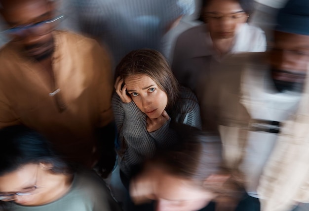 Alone in a room full of people. shot of a young woman sitting on the floor with people around her.