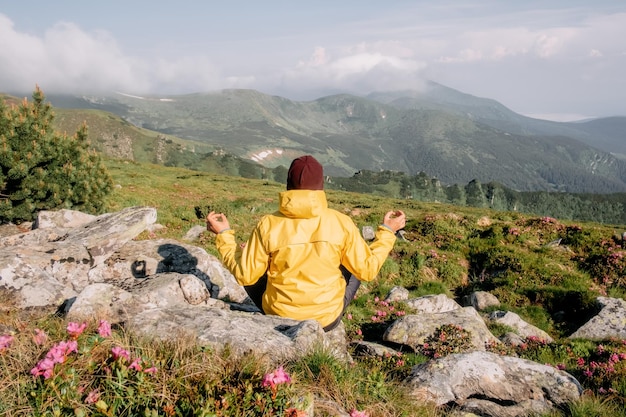노란색 재킷을 입은 혼자 높은 산을 명상하는 관광객