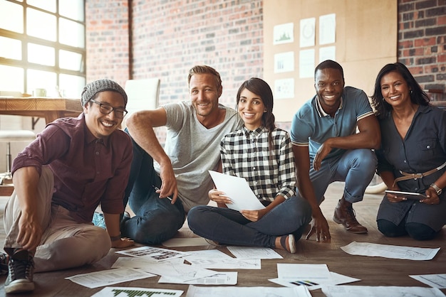 Alone we are one drop together we are an ocean Shot of a team of entrepreneurs collaborating and sitting on the floor in a modern office