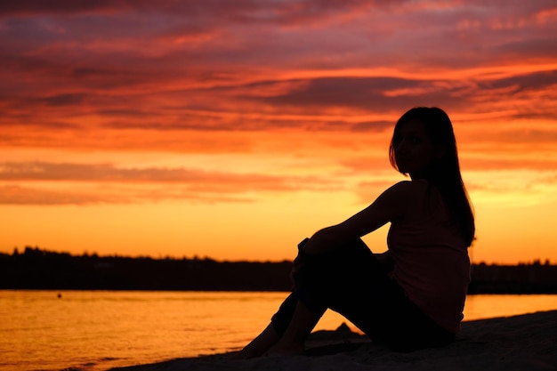 Alone woman sitting watching the sunset sunrise