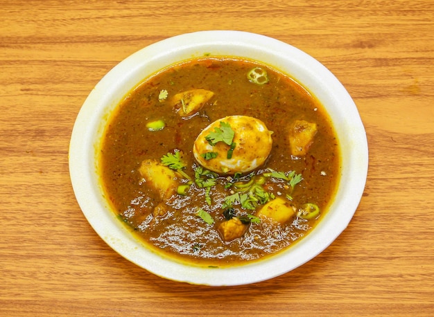 Aloo anday shorba или карри из яичного картофеля подается в тарелке, изолированной на столе, с видом на индийскую и пакистанскую острую пищу