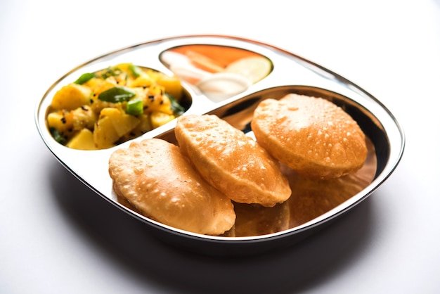 Photo aloo fry or bombay potatoes and puri or poori in a stainless steel oval plate, selective focus