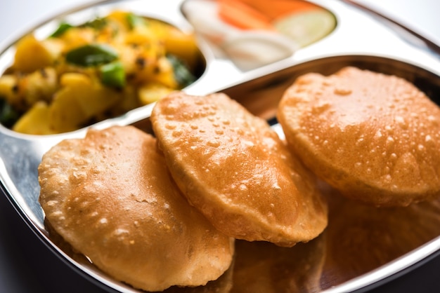 Aloo Fry OR Bombay potatoes and puri or Poori in a stainless steel oval plate, selective focus