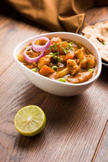 Aloo Gobi mutter is a famous Indian curry dish with potatoes and cauliflower and green peas, selective focus