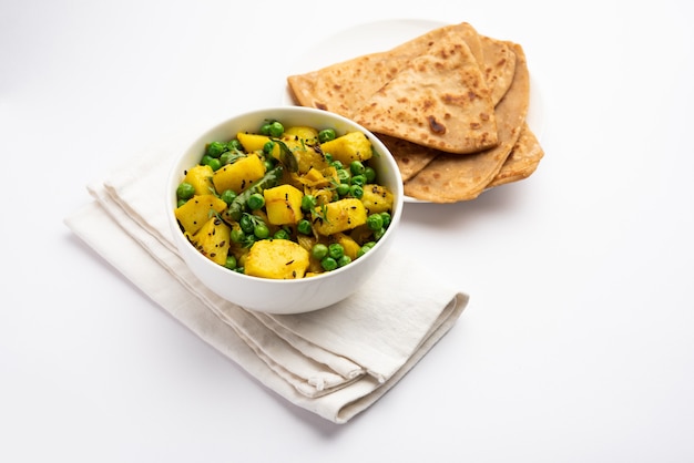 Aloo Mutter 또는 Matar aalu 드라이 sabzi, 인도 감자 및 녹색 완두콩은 향신료와 함께 튀겨지고 고수 잎으로 장식됩니다. roti 또는 chapati와 함께 제공