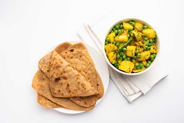 Foto aloo mutter o matar aalu dry sabzi, patate indiane e piselli fritti insieme alle spezie e guarniti con foglie di coriandolo. servito con roti o chapati