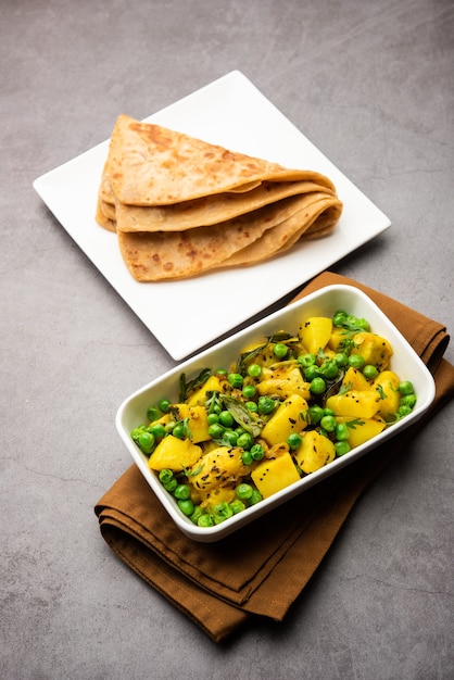 Aloo Mutter of Matar aalu droge sabzi, Indiase aardappel en groene erwten samen gebakken met kruiden en gegarneerd met korianderblaadjes. geserveerd met roti of chapati