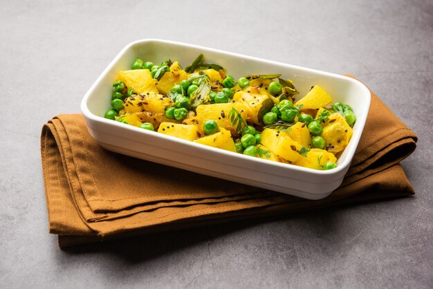 Aloo Mutter of Matar aalu droge sabzi, Indiase aardappel en groene erwten samen gebakken met kruiden en gegarneerd met korianderblaadjes. geserveerd met roti of chapati