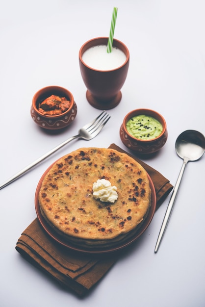 Алоо Парата или Индийская картофельная лепешка с начинкой из сливочного масла. Подается со свежим сладким ласси, чатни и маринованными огурцами. выборочный фокус
